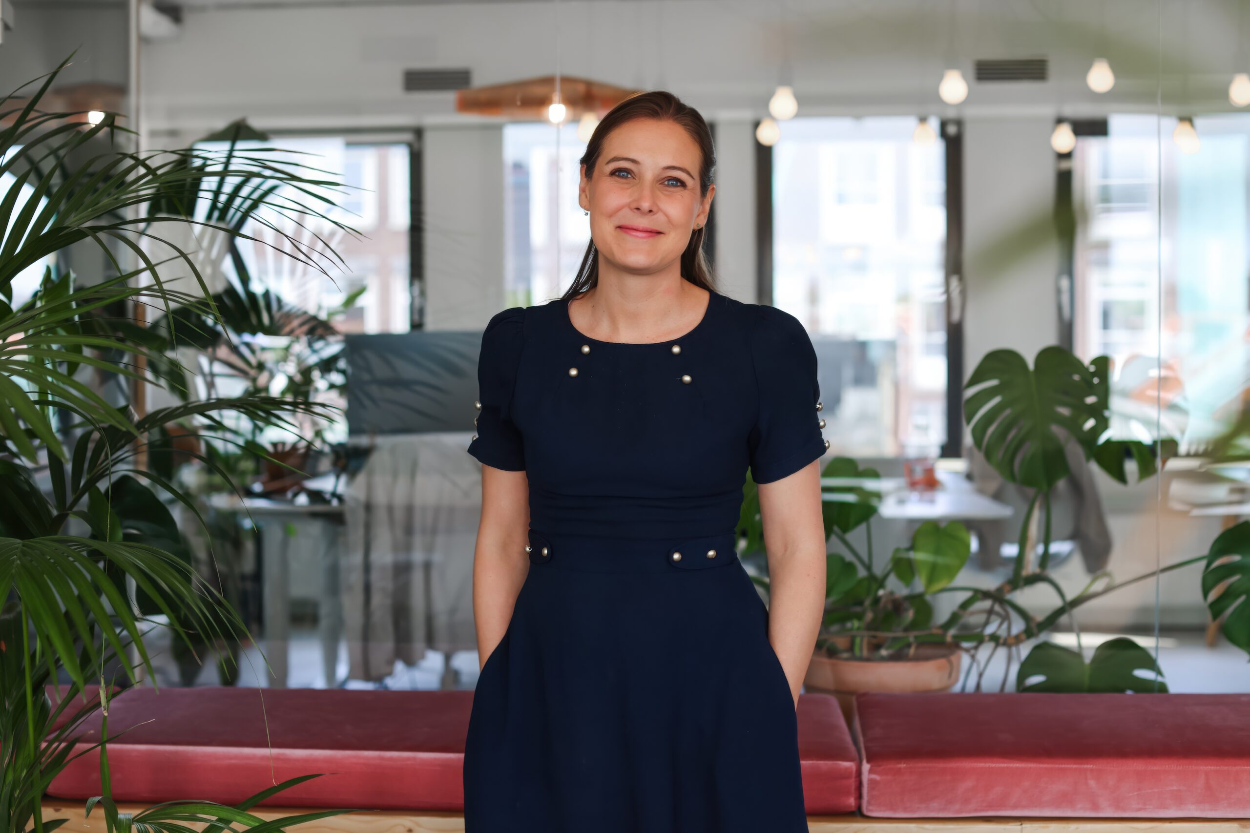 A woman standing in a brightly lit office decorated with plants