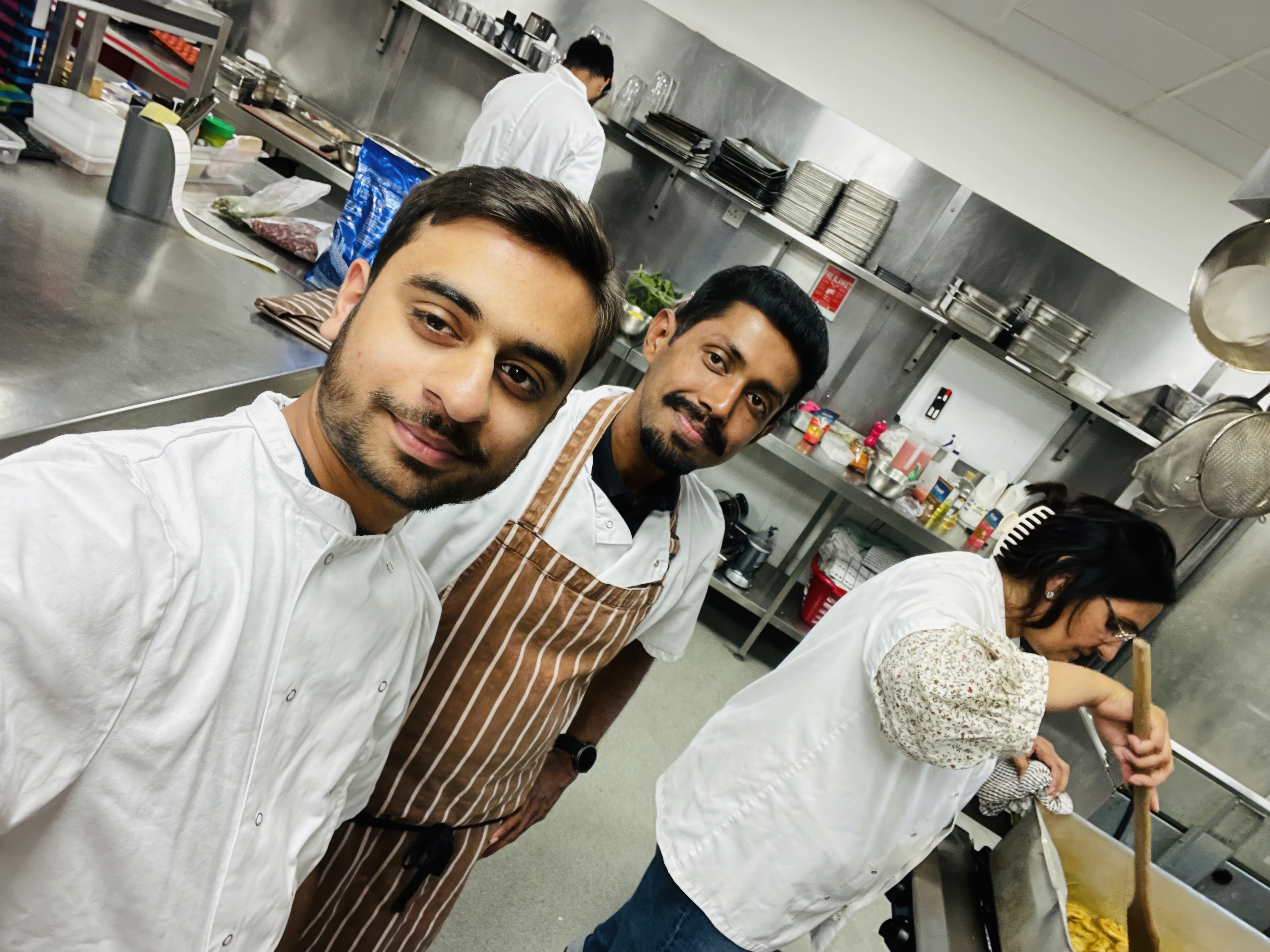 A young man standing with an older man and woman, smiling at the camera as one takes a selfie